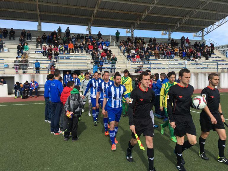 Los jugadores de ambos equipos salen al campo junto al trío arbitral