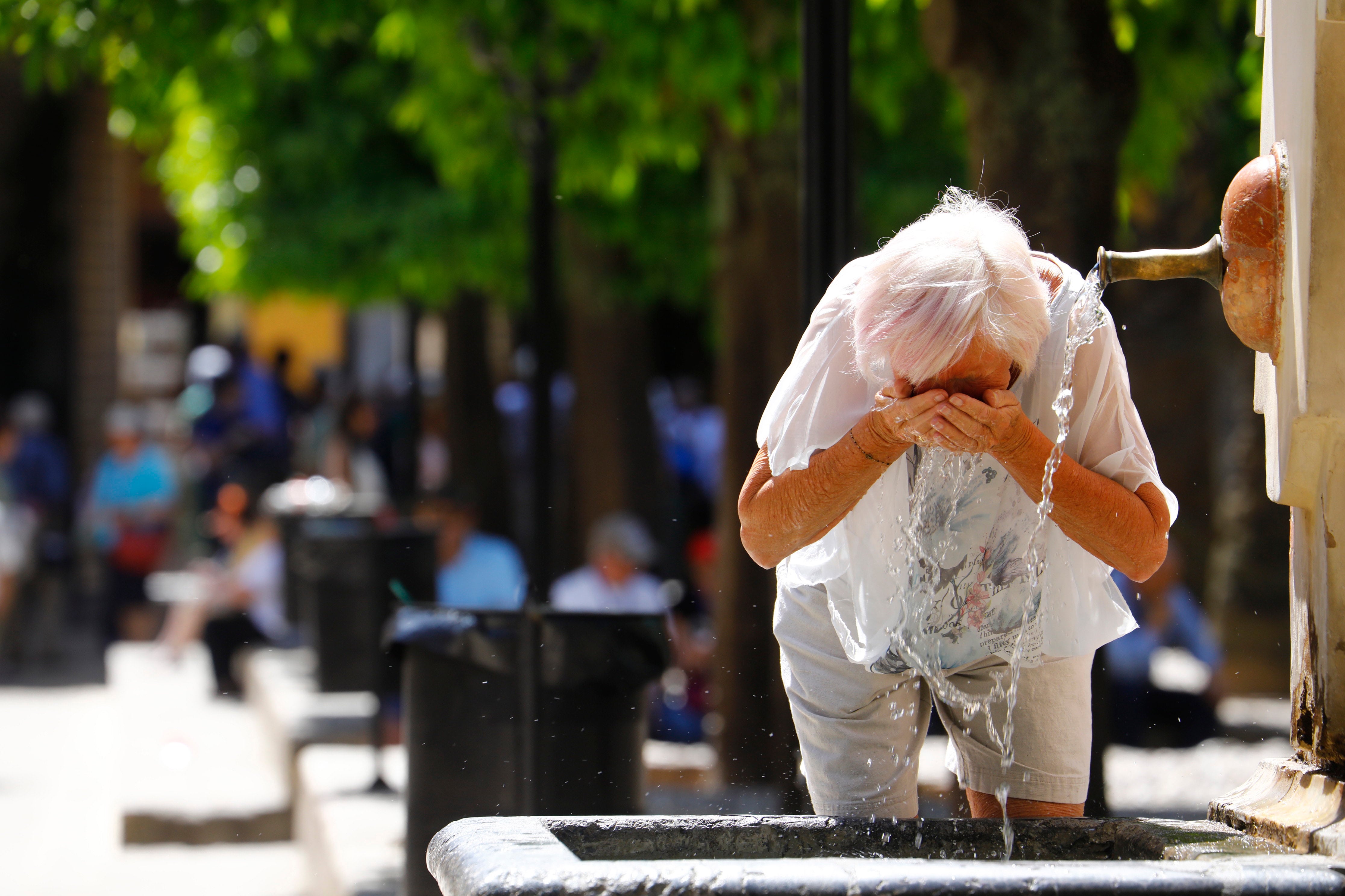 Una mujer se refresca en una fuente de Córdoba