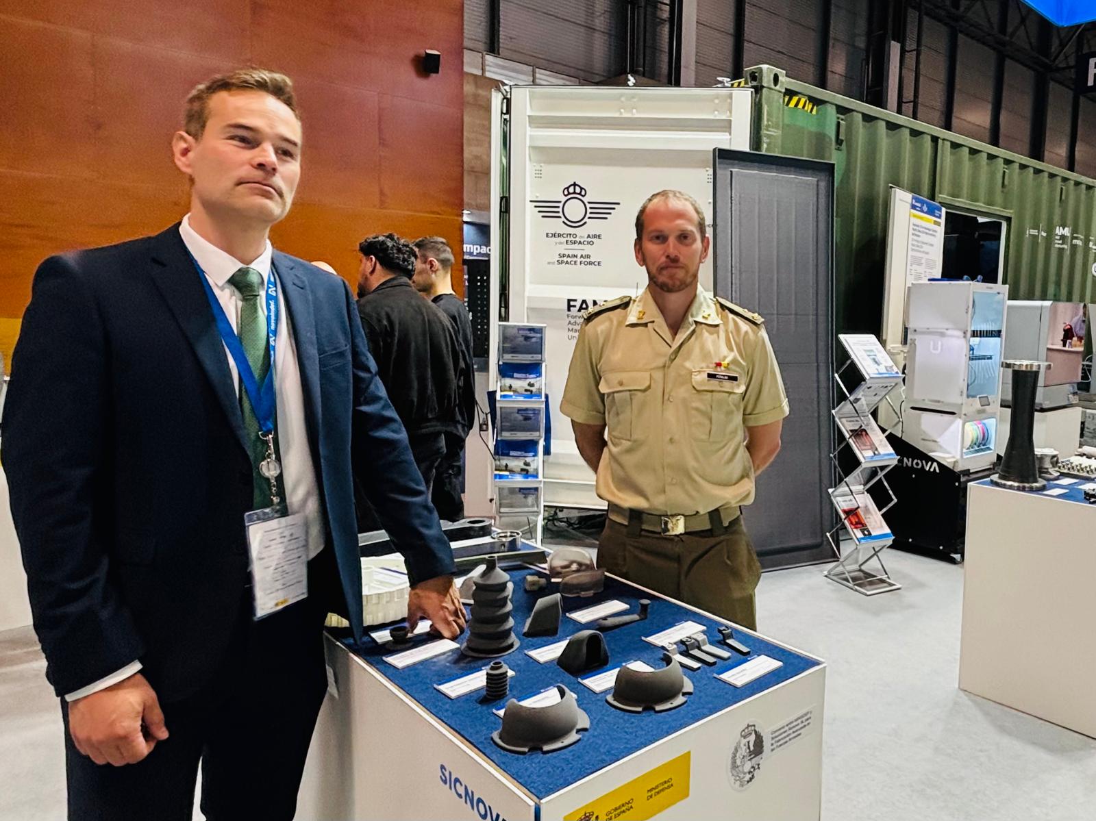 Ramón González, responsable de Fabricación Avanzada de Sicnova (izquierda); y el capitán Carlos Peñalba, director técnico del centro de fabricación de piezas del MALE (derecha). Ambos posan en el stand de Sicnova en FEINDEF
