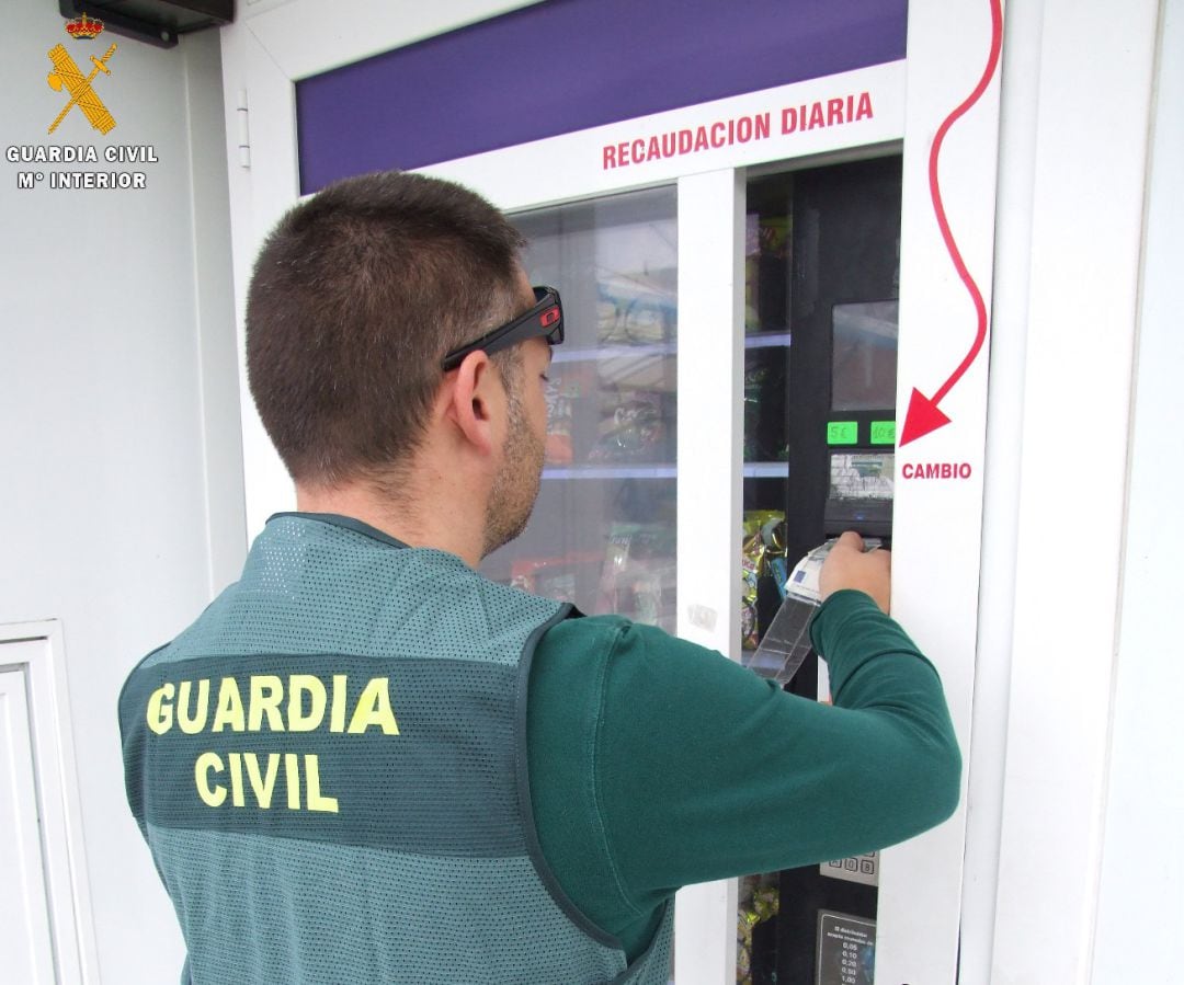 Un agente de la Guardia Civil simula la manipulación que los estafadores realizaban en la máquina expendedora.