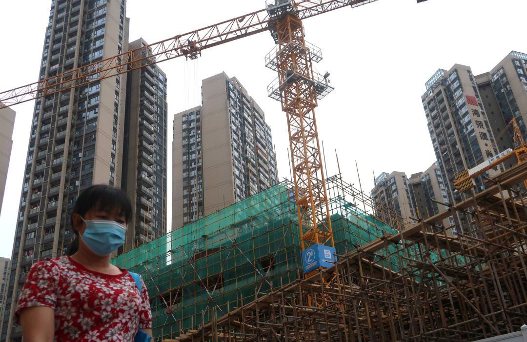 Una mujer protegida con una mascarilla camina por una zona en construcción de Shenzhen (China).