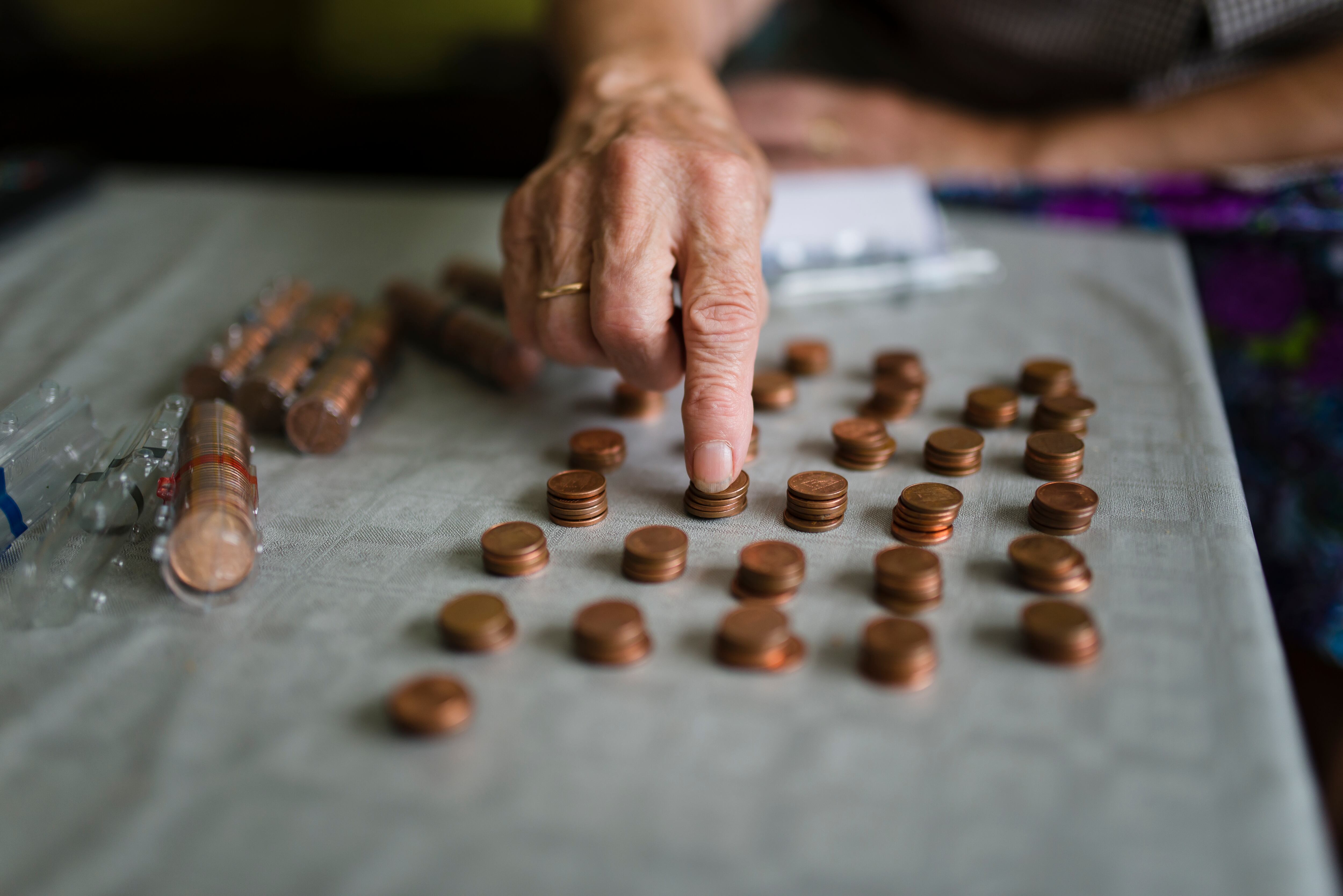 Una mujer mayor cuenta unas monedas de céntimo.