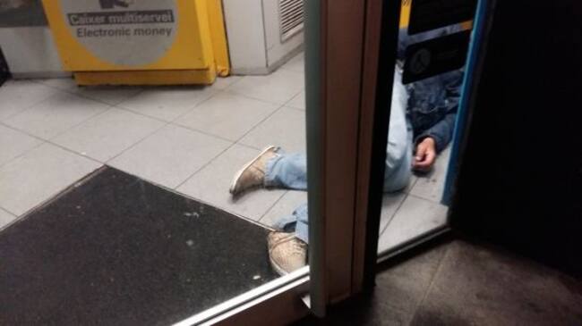 Una persona sense llar dormint a l'interior d'un caixer