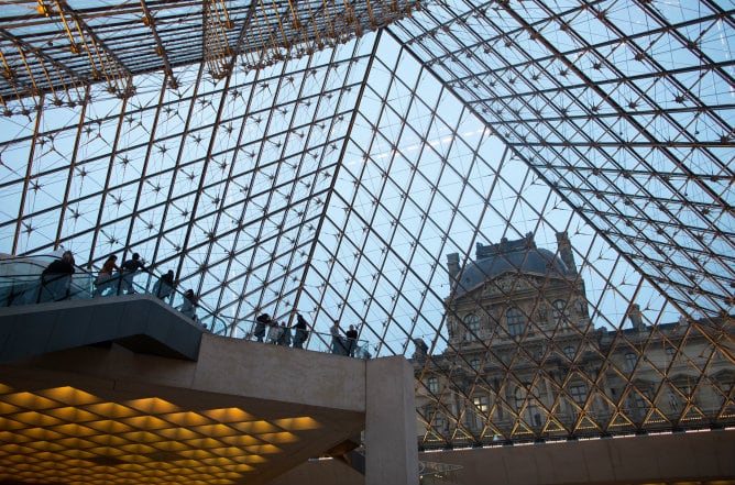 Un grupo de turistas visita la pirámide de vídrio y metal del Louvre