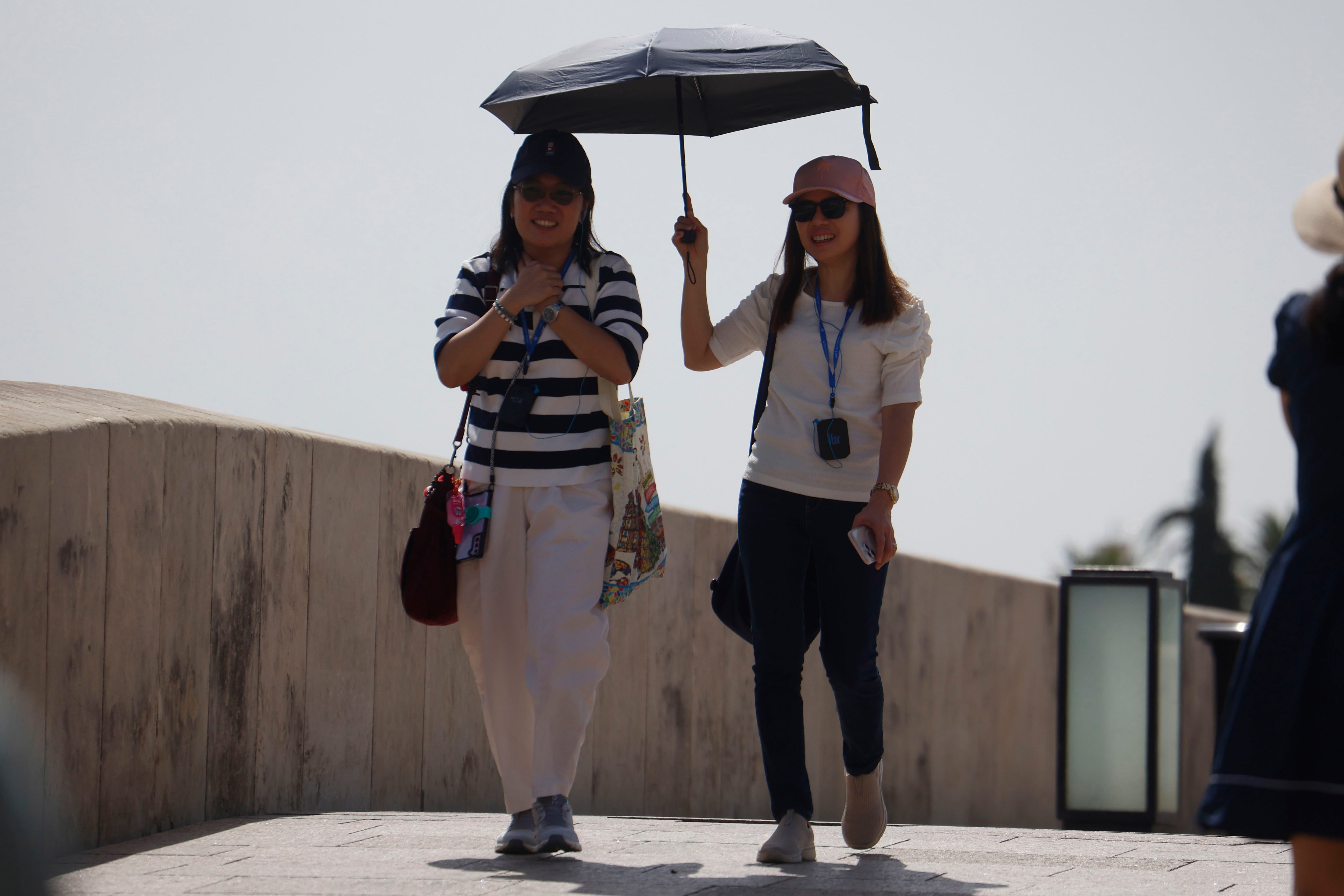 CÓRDOBA, 10/08/2025.- Dos personas se protegen del sol con un paraguas. EFE/Salas