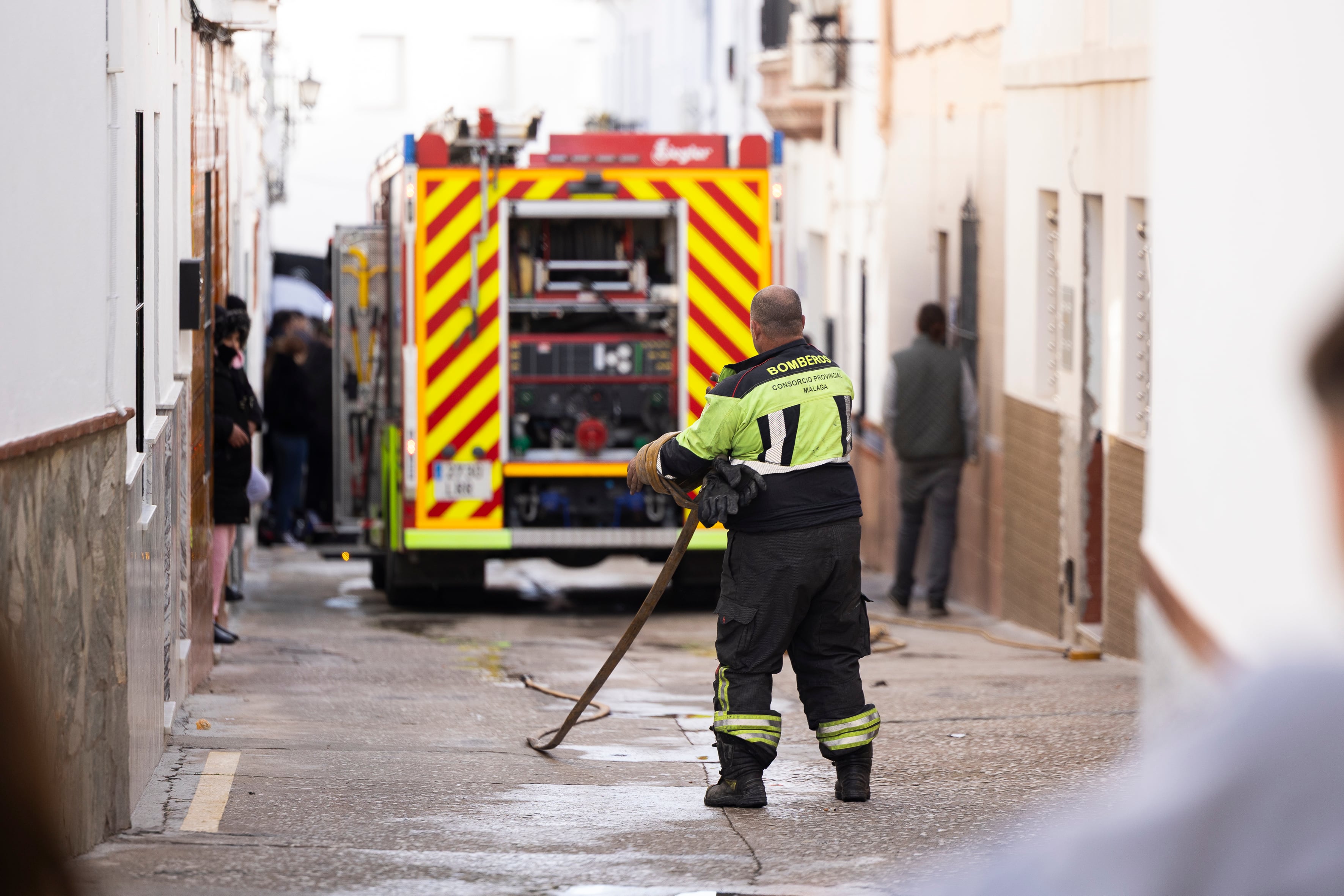 ALHAURÍN EL GRANDE (MÁLAGA), 25/12/2025.- El Ayuntamiento de la localidad malagueña de Alhaurín el Grande ha decretado un día de luto oficial -este viernes 26 de diciembre- por el fallecimiento este jueves de dos menores de 15 y 16 años en el incendio de una vivienda del municipio. en la imagen, un bombero recoge la manguera en la calle San Rafael donde ha ocurrido le siniestro. EFE/Carlos Díaz