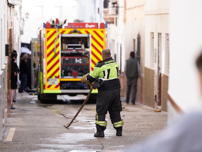 ALHAURÍN EL GRANDE (MÁLAGA), 25/12/2025.- El Ayuntamiento de la localidad malagueña de Alhaurín el Grande ha decretado un día de luto oficial -este viernes 26 de diciembre- por el fallecimiento este jueves de dos menores de 15 y 16 años en el incendio de una vivienda del municipio. en la imagen, un bombero recoge la manguera en la calle San Rafael donde ha ocurrido le siniestro. EFE/Carlos Díaz