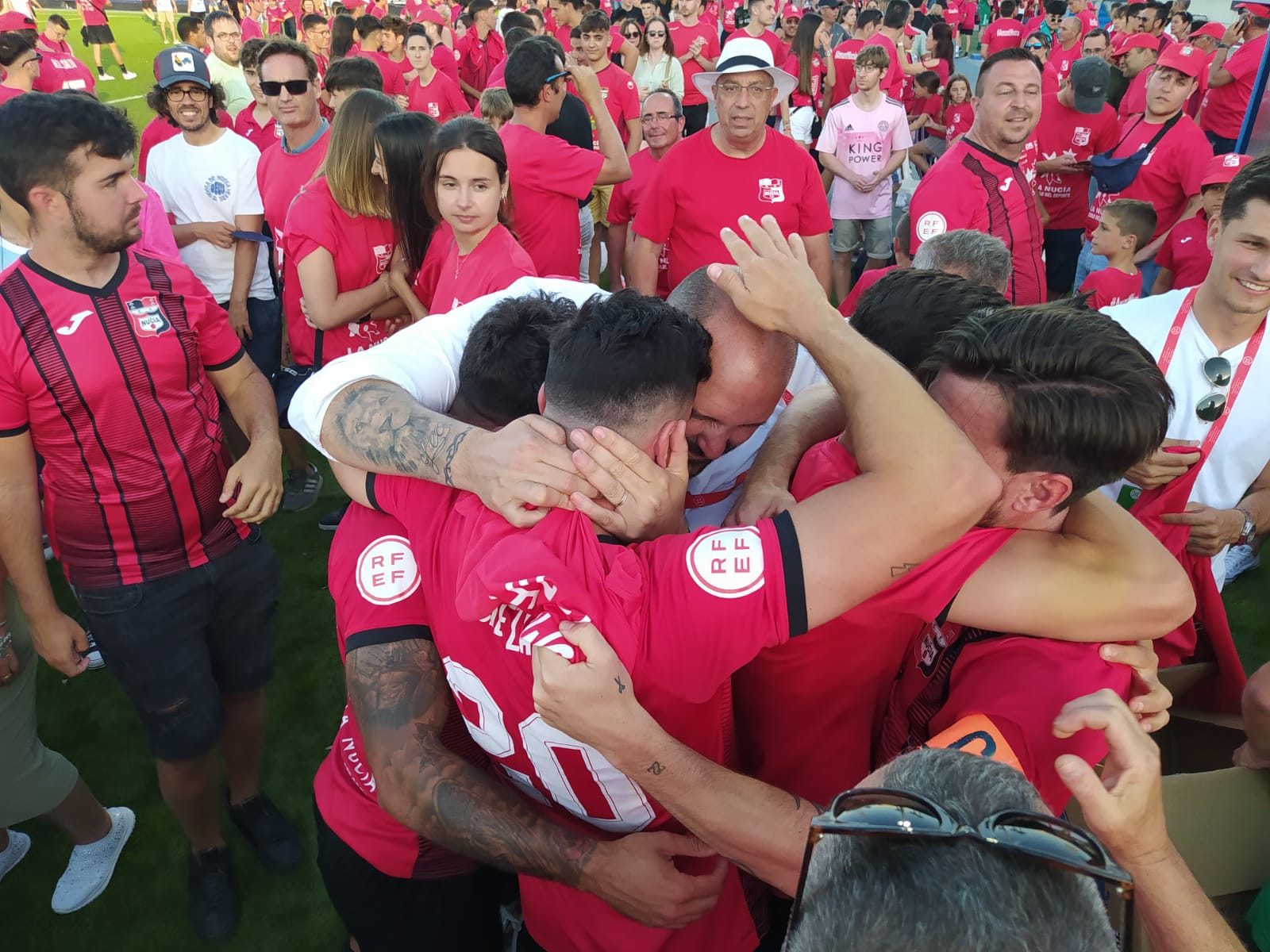 Kiko Lacasa y los jugadores del C.F. La Nucía celebrando sobre el césped el ascenso a Primera RFEF / JORGE GARCÍA PÉREZ