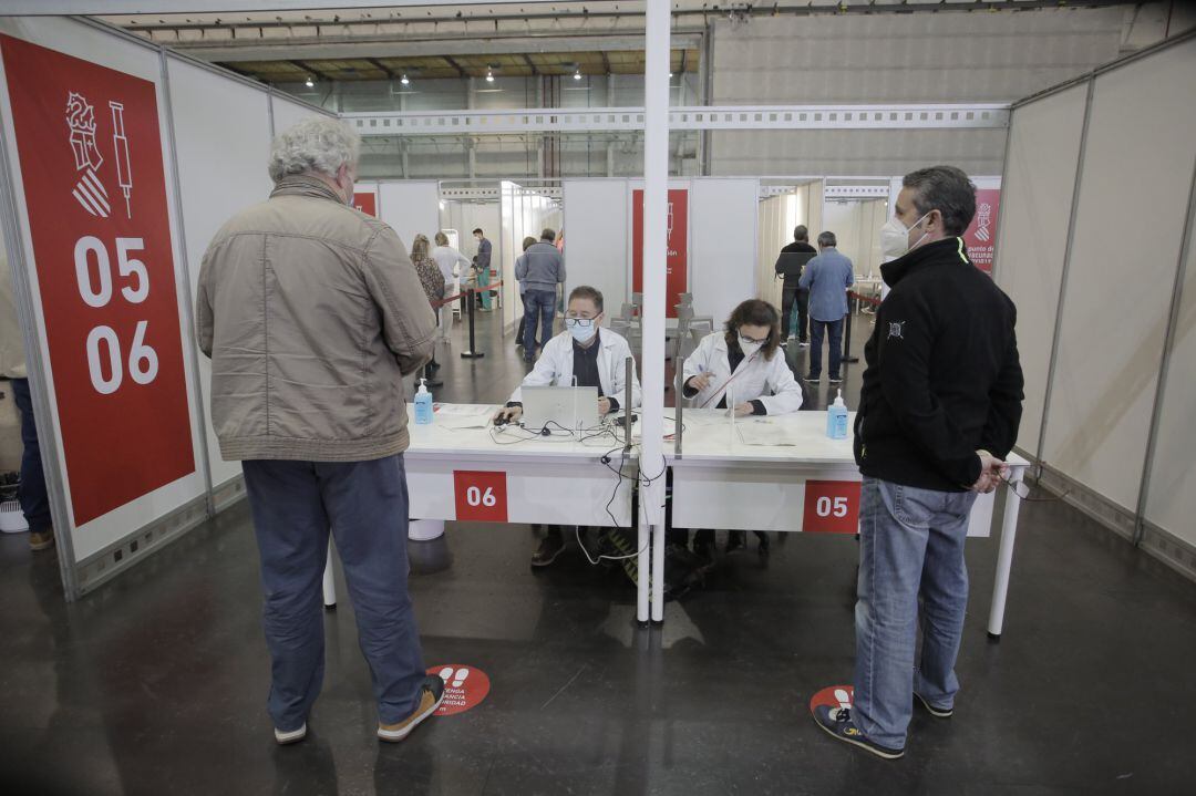 Dos hombres esperan para ser vacunadas en el primer día de la vacunación masiva en la Ciudad de la Luz de Alicante.