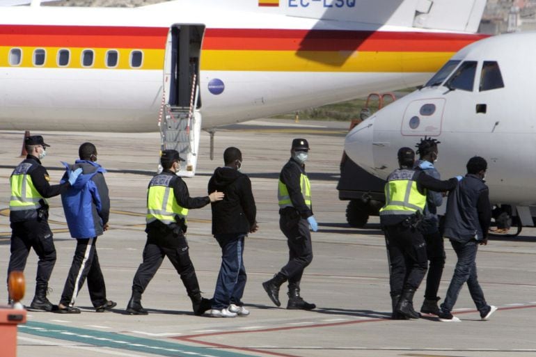 Agentes de la Policía Nacional trasladan hasta el avión a un grupo de inmigrantes desde Melilla un CETI de la Península