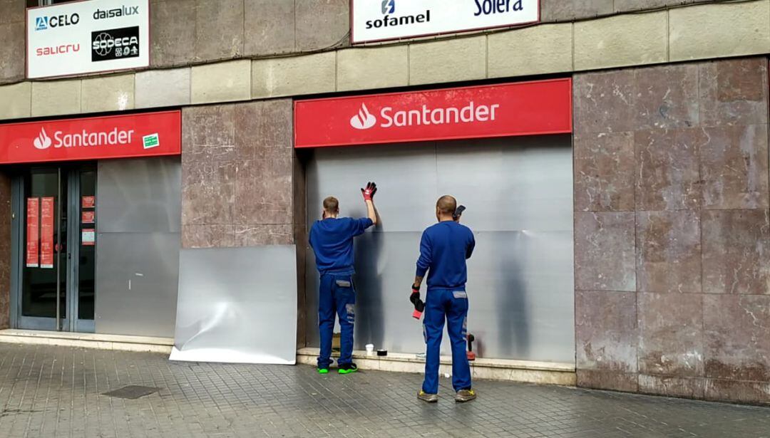 Dos operaris col·loquen planxes d&#039;acer al Santander de Gran Via amb Sicília