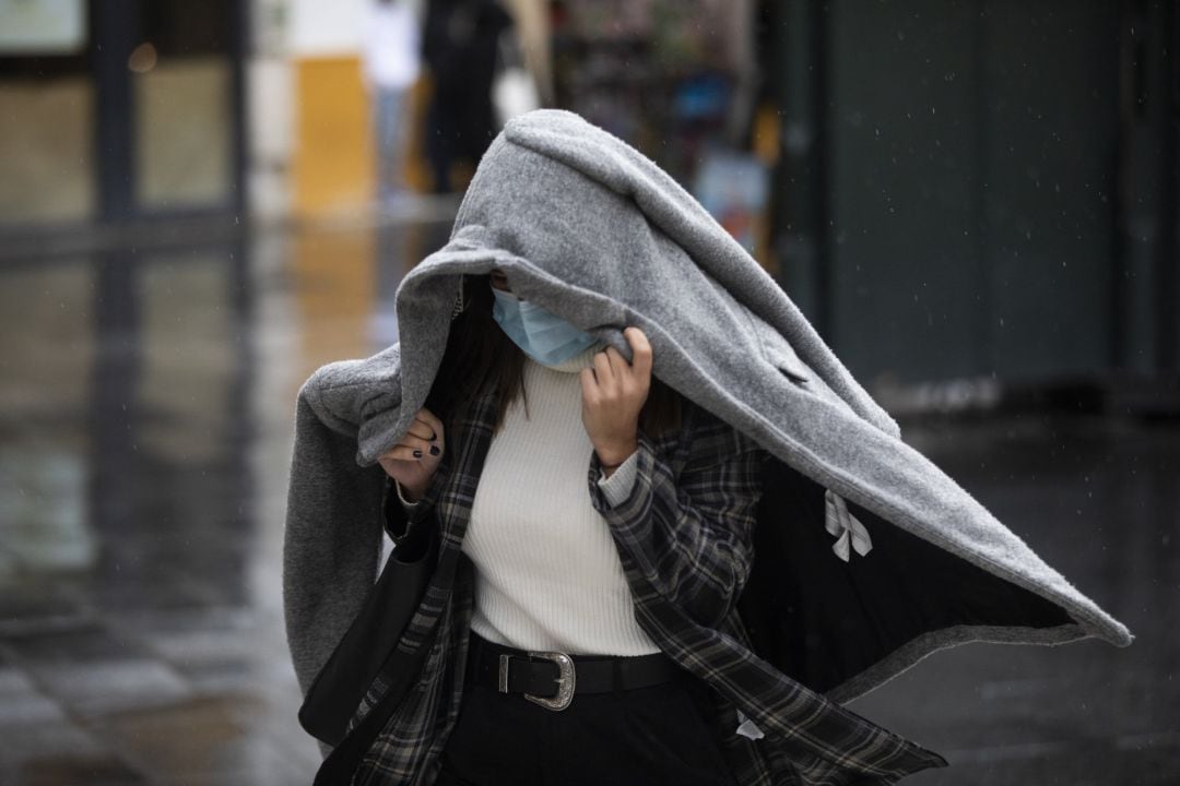 Una persona se protege de la lluvia con un abrigo.