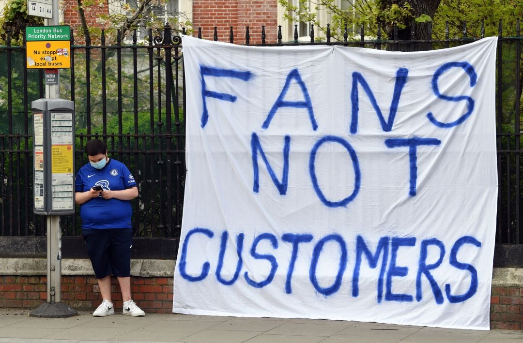 Un seguidor del Chelsea al lado de una pancarta de protesta contra la creación de la Superliga