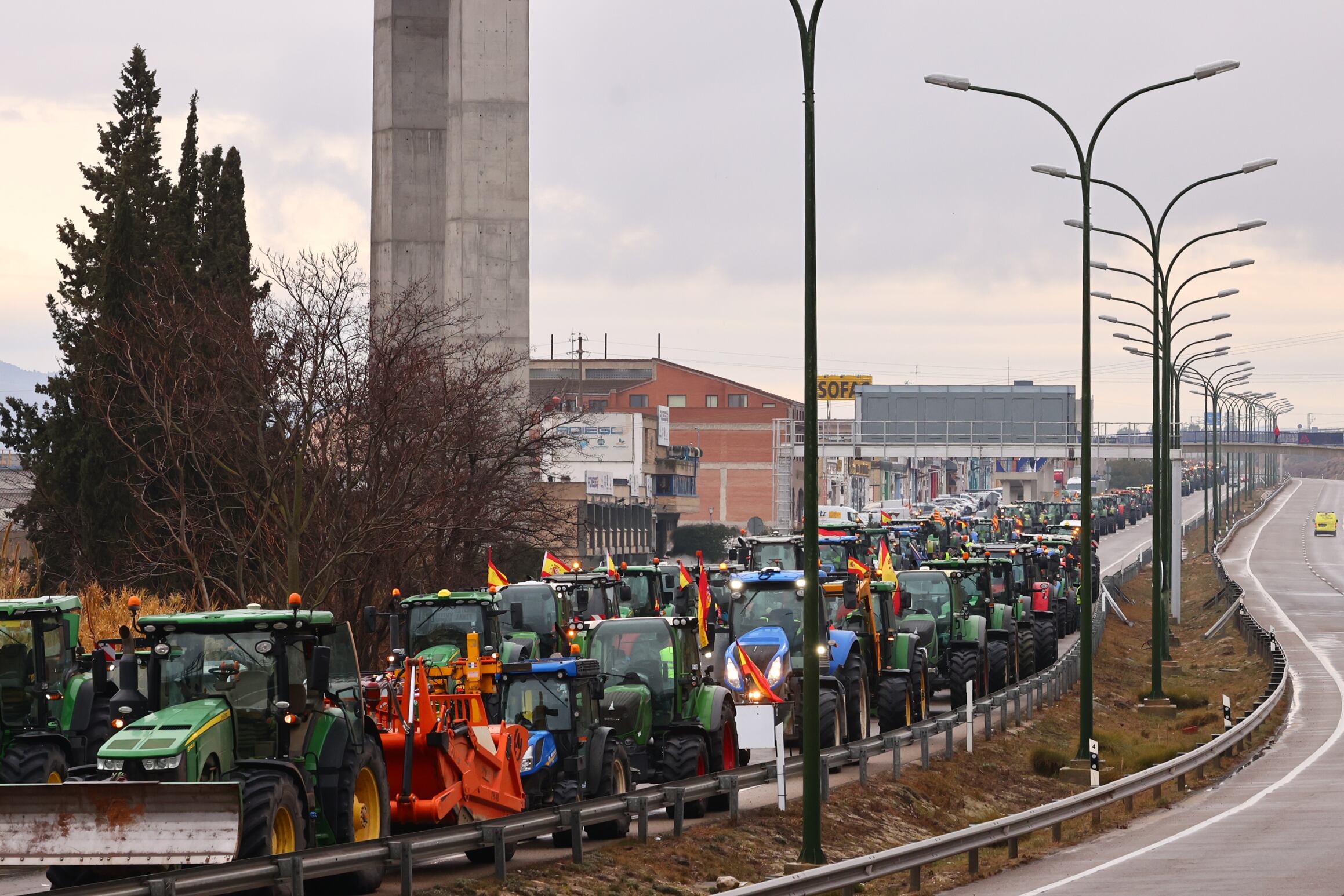 CUARTE DE HUERVA (ZARAGOZA), 09/02/2024.- Más de 200 tractores en la N-330 pasan por la localidad de Cuarte de Huerva de camino a Zaragoza este viernes. Las protestas de los agricultores no cesan, inician este viernes su cuarta jornada con carreteras cortadas o con circulación lenta por las movilizaciones. EFE/ Toni Galán
