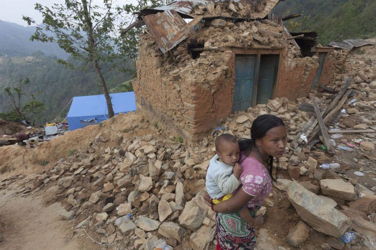 NPL56. Kathmandu (Nepal), 10/05/2015.- A woman carrying her children walks amidst destroyed houses after the earthquake of 25 April in Majuwa village on the outskirts of Kathmandu, Nepal 10 May 2015. The official confirmed death toll of the 7.8-magnitude earthquake of 25 April stood at over 7,900 people, while some 297,266 damaged houses were recorded on 09 May. The numbers are expected to rise when more isolated areas will be accessed. (Terremoto/sismo) EFE/EPA/HEMANTA SHRESTHA