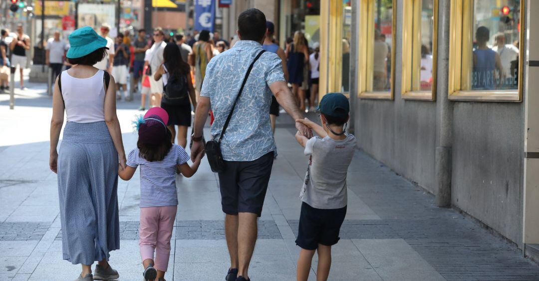 Una familia pasea de la mano por una calle 