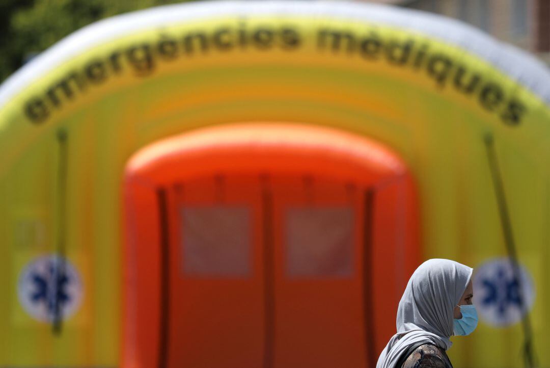 Una mujer con una máscara protectora pasa frente a un hospital de campaña en las afueras del hospital Arnau de Vilanova, en Lleida