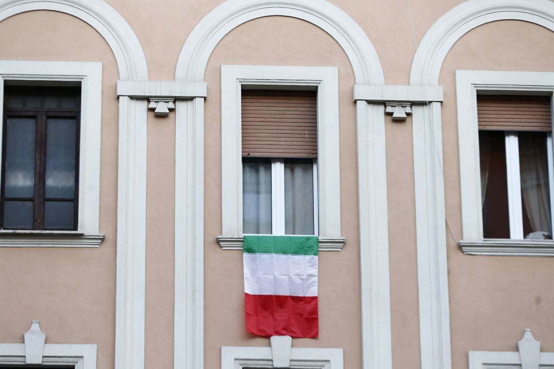 Una bandera de Italia cuelga de una ventana de un apartamento en Roma