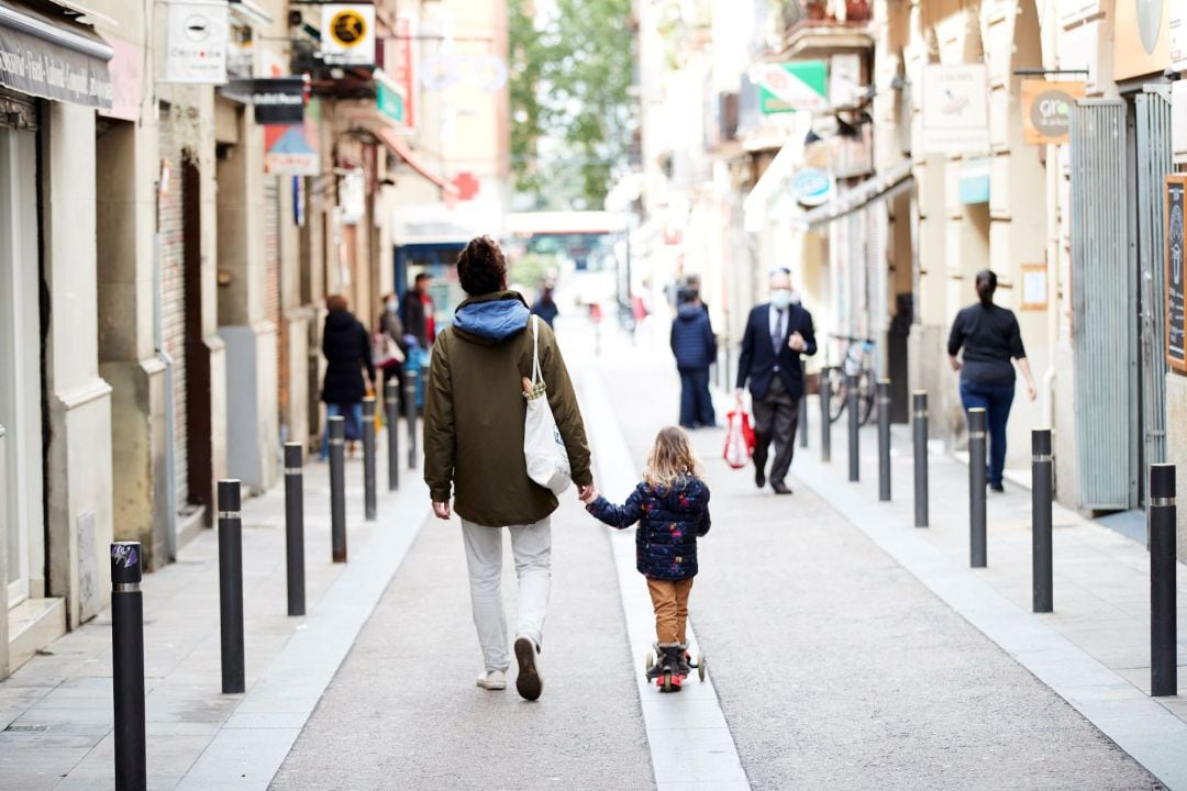 Un hombre y una niña caminan por el barrio de Gracia de Barcelona