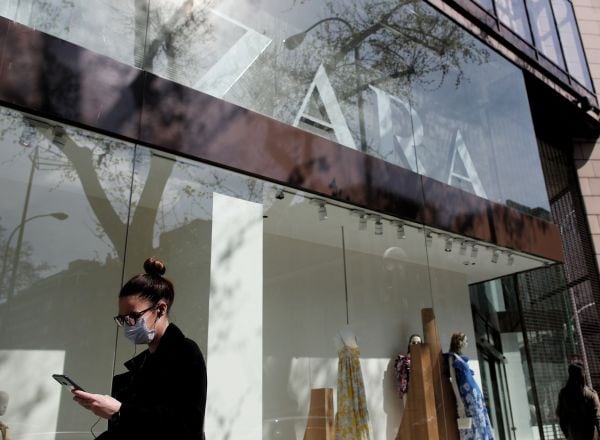 Una mujer con mascarilla pasa junto al escaparate de la tienda Zara de la Calle Princesa de Madrid del grupo Inditex. Archivo.