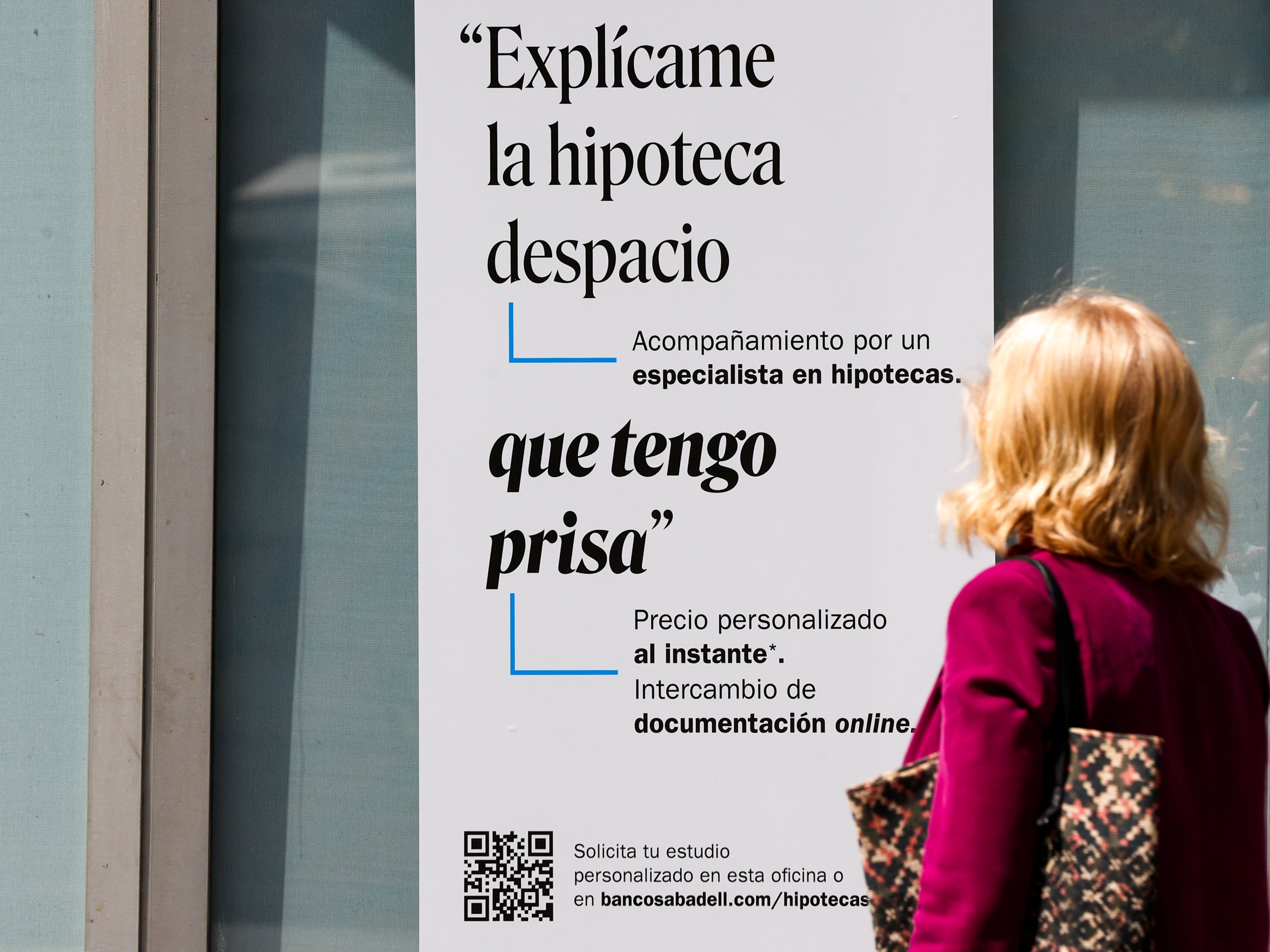 Una mujer ante un cartel bancario sobre las hipotecas.