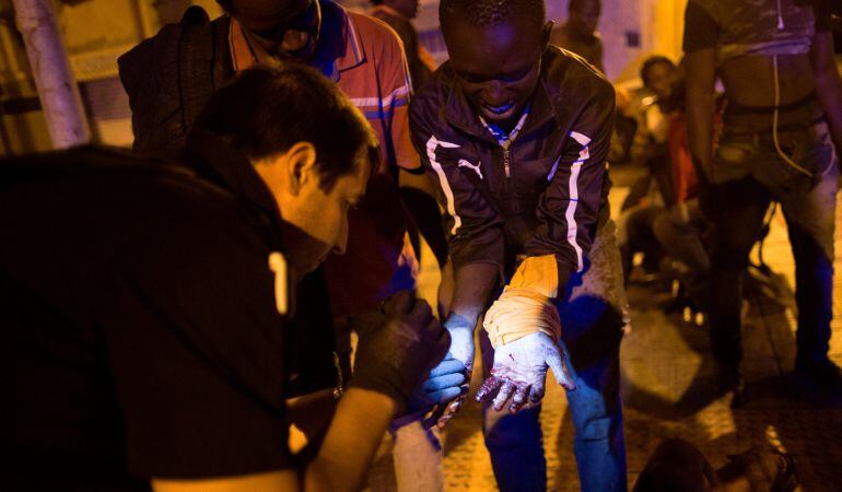 Un policía inspecciona a una de las personas que han saltado la valla de la frontera de Ceuta.