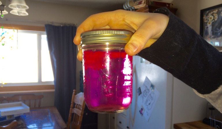 Una habitante recoge el agua de color rosa.