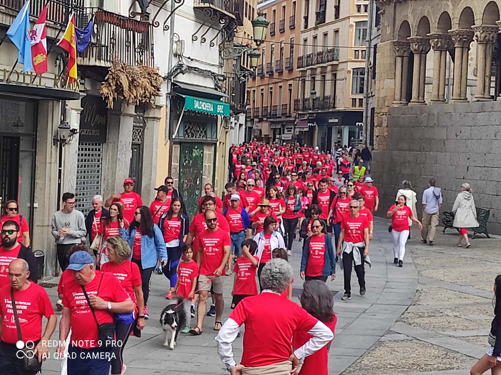 Participantes en la V Marcha Parkinson Segovia a su paso por la iglesia San Martín (Calle Real)