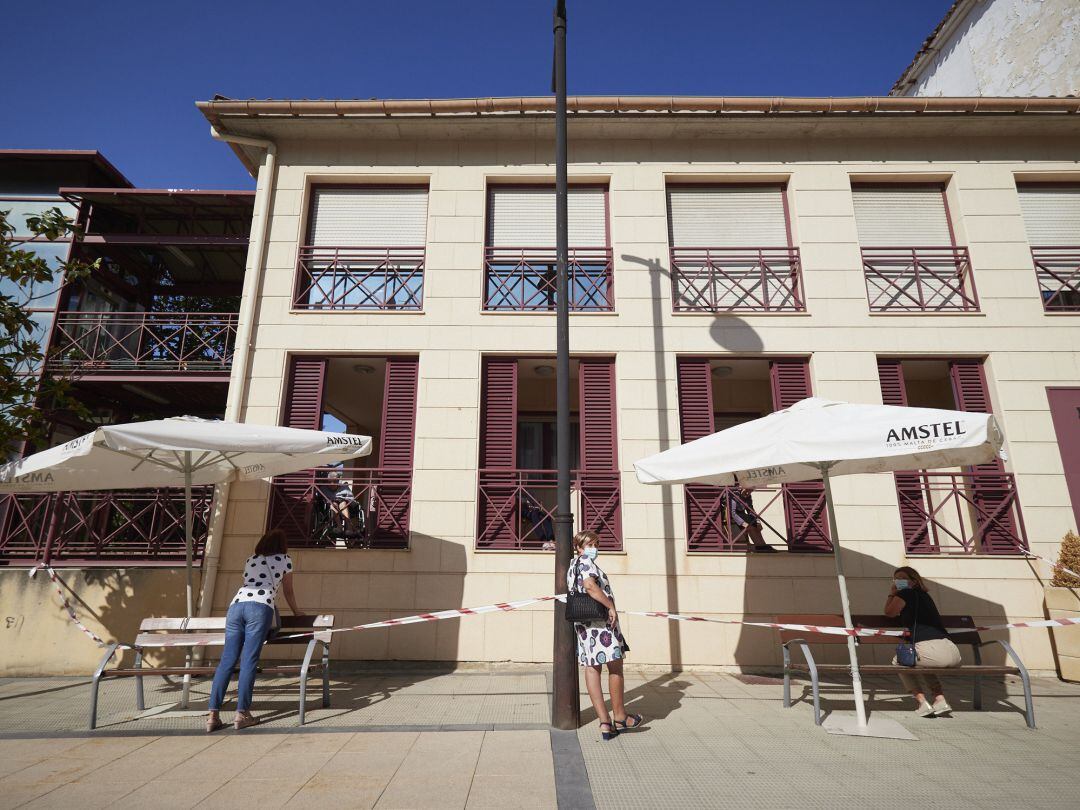 Varias vecinas de la localidad de Peralta visitan a sus familiares desde el exterior de una residencia de mayores, en Peralta