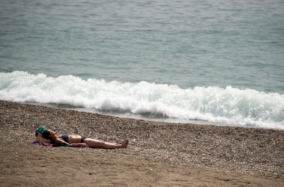 Una mujer toma el sol en la playa de la Malagueta.