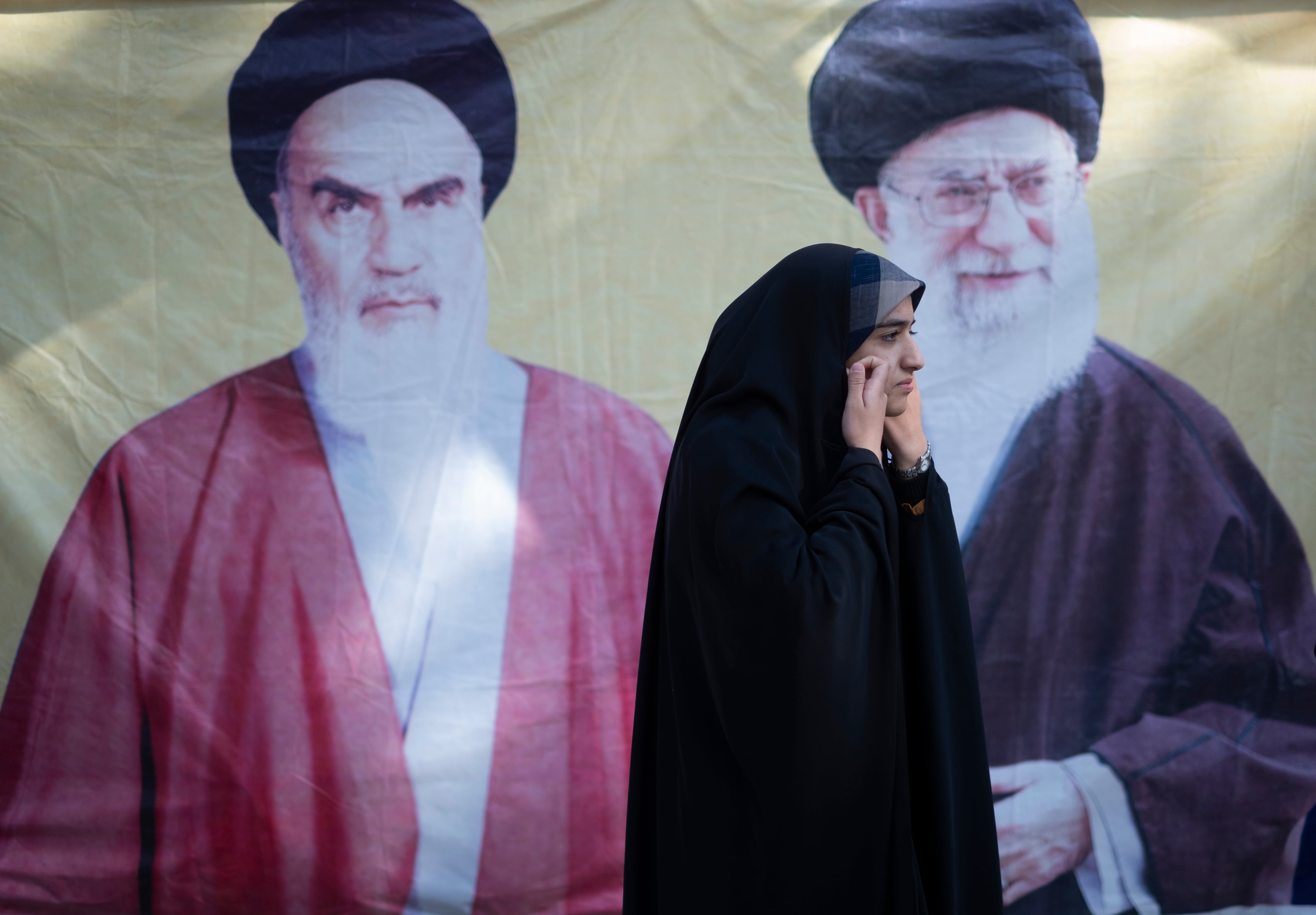 Una mujer pasa por delante de un cartel del líder supremo de Irán, el ayatollah Ali Khamenei, y del actual líder, el ayatollah Ruhollah Khomeini