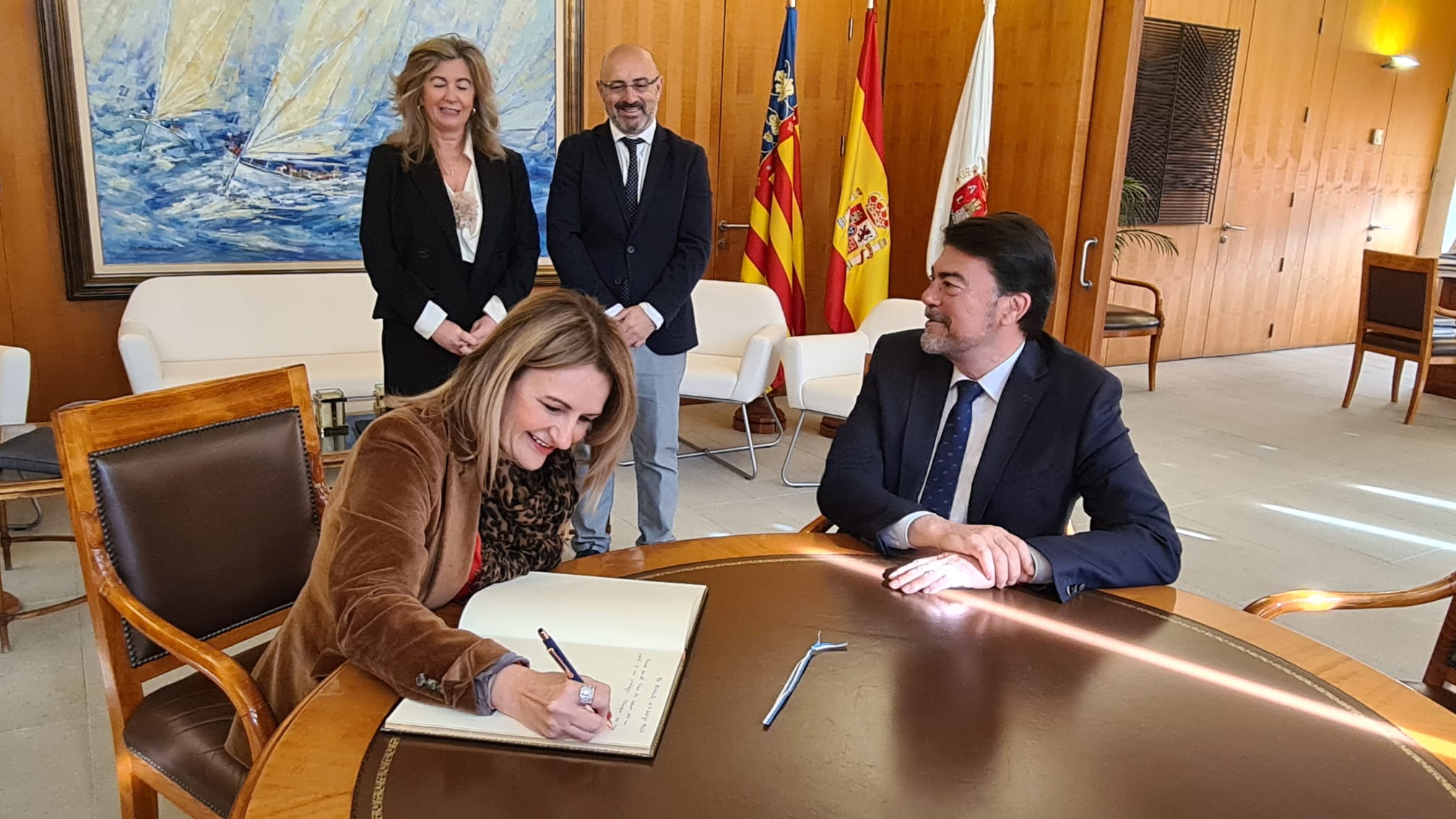 El alcalde Barcala observa como la consellera Nuria Montes firma el libro de visitantes ilustres de Alcaldía