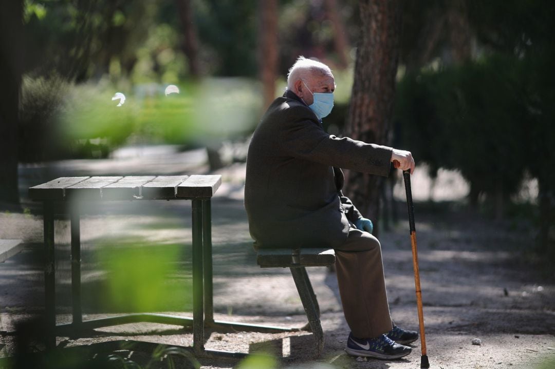 Un anciano con mascarilla descansa en el Parque Calero (Madrid) 