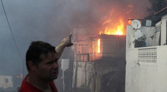 Un hombre señala una casa en llamas en Funchal.