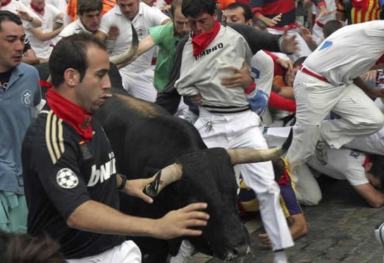 Un toro de la ganadería sevillana de Dolores Aguirre crea una situación de peligro a su paso por la curva de Telefónica durante el tercer encierro de los sanfermines 2011