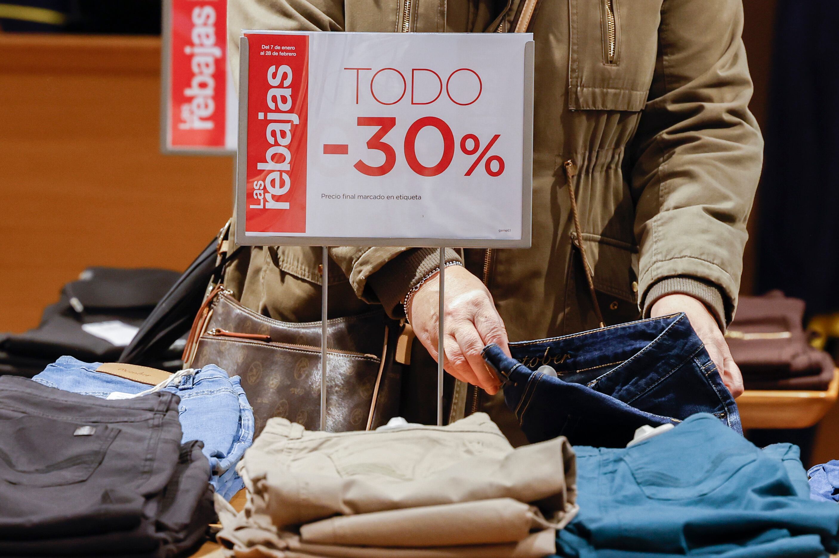 MADRID, 07/01/2023.- Una consumidora revisa varias prendas en el primer día de las rebajas de enero este sábado en unos grandes almacenes en el centro de Madrid. Las rebajas de enero comienzan hoy en la mayor parte de los comercios españoles, un periodo de descuentos que se prolongará hasta finales de febrero y en el que se esperan compras con un presupuesto más reducido por los elevados precios de los últimos meses. EFE/ J.J. Guillén
