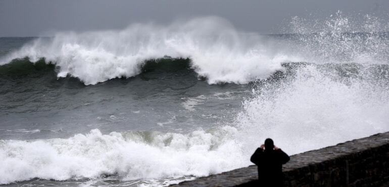 Un hombre fotografía una ola en el paseo de La Zurriola de San Sebastián, donde hoy se ha decretado la alerta naranja por fenómenos costeros