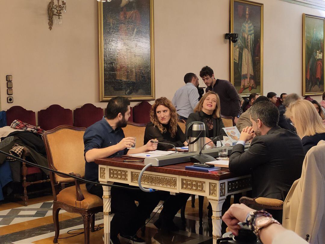 Los concejales de Somos durante el pleno de presupuestos de este viernes. Rubén Rosón charla con su compañera Anabel Santiago.