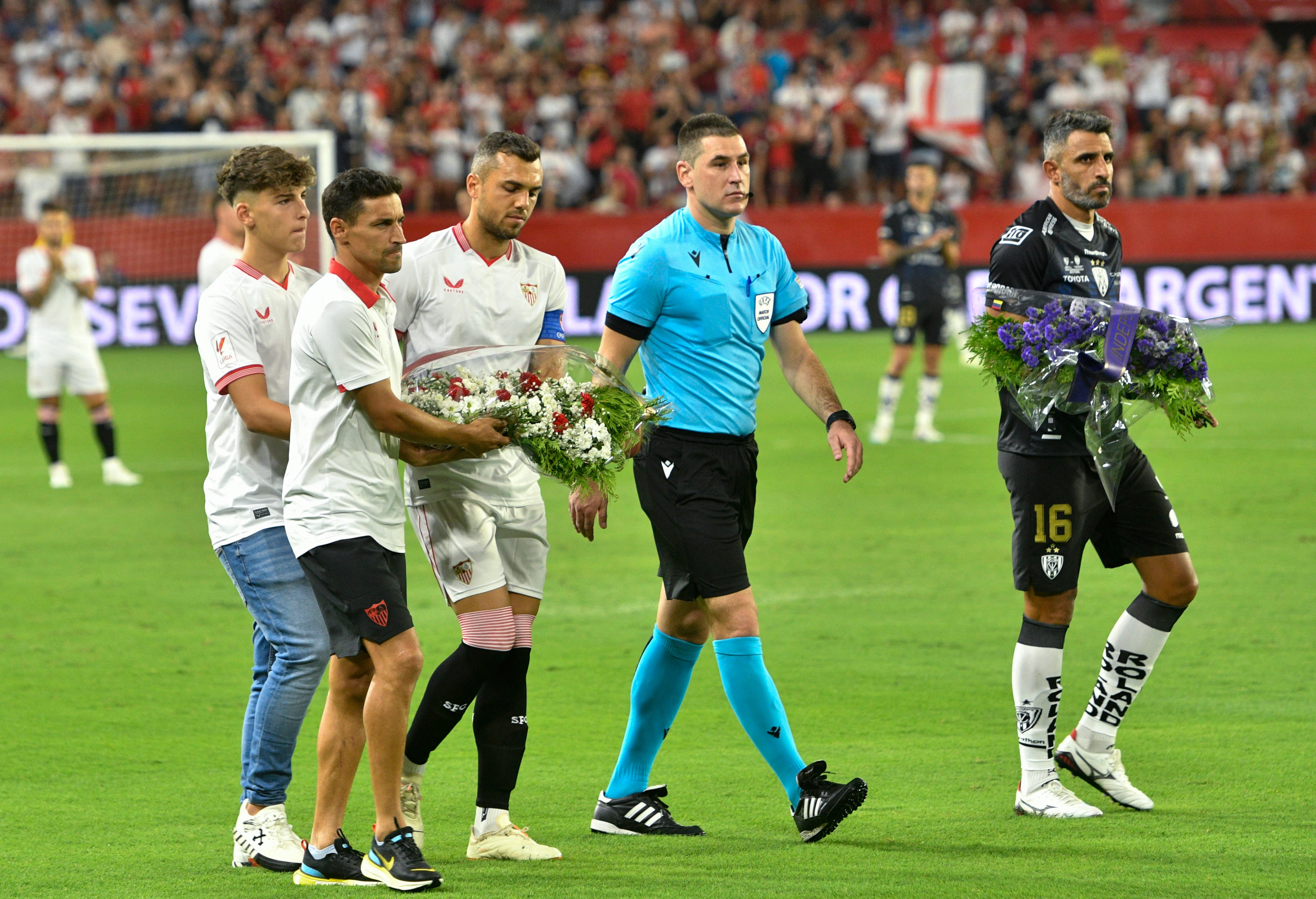 SEVILLA. 19/07/2023. - Los capitanes del Sevilla FC, Jesús Navas (2i) y Jordán (3i), portan un ramo de flores junto al hijo de Antonio Puerta, Aitor Puerta (i), el capitán del Independiente del Valle, Cristian Pellerano (d) y el árbitro del encuentro, Rade Obrenovic, durante el partido de la UEFA Conmebol Club Challenge y XII Trofeo Antonio Puerta que disputan hoy miércoles en el estadio Ramón Sánchez Pizjúan de Sevilla. EFE/ Raúl Caro.
