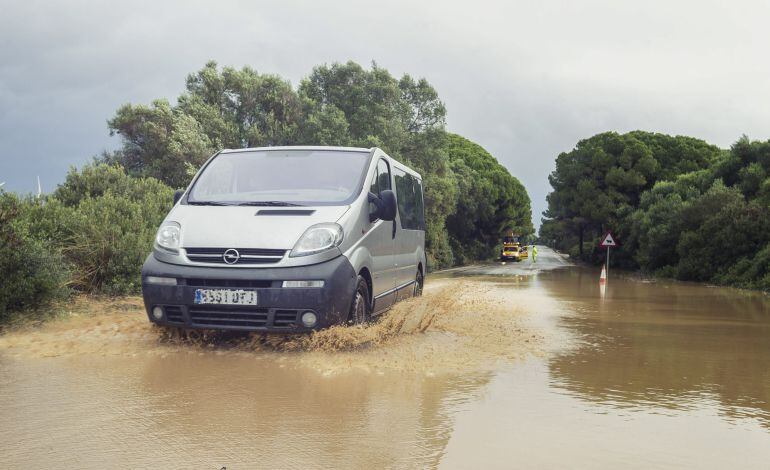 Un vehículo atraviesa una carretera inundada en la carretera A-408 a la altura de Puerto real (Cádiz).