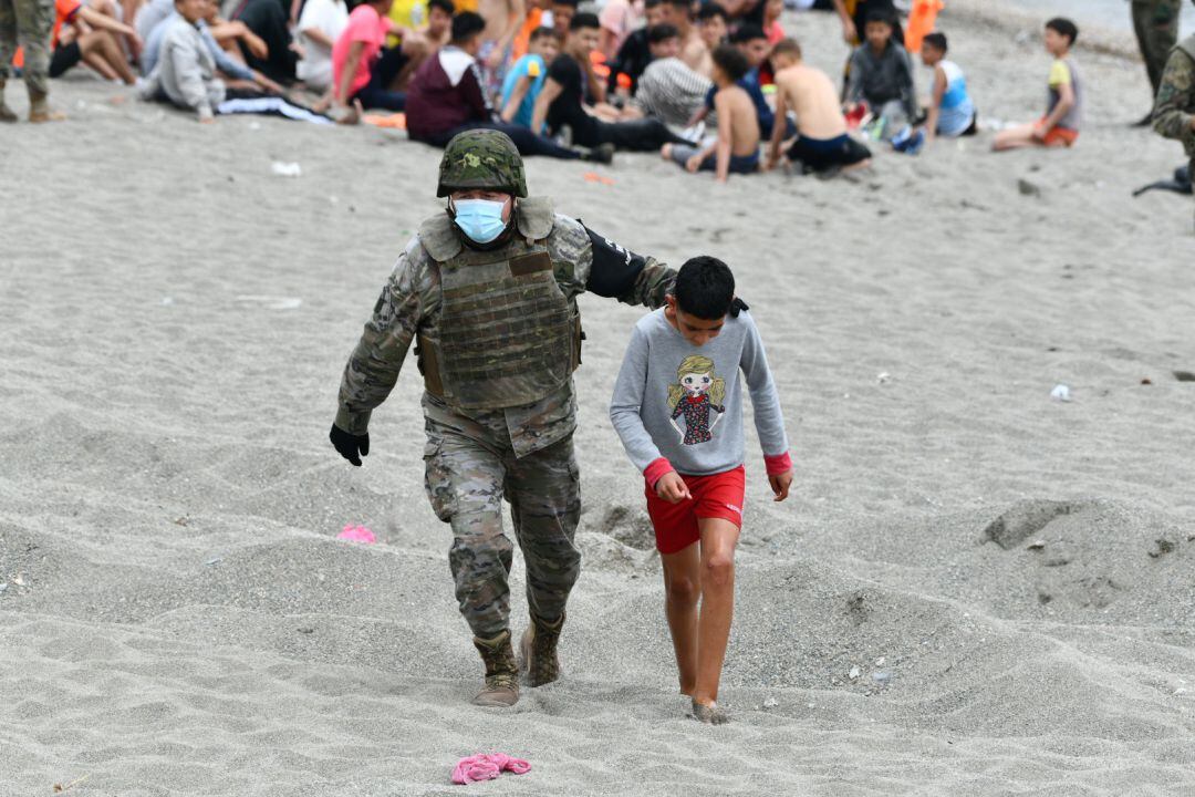 Un militar del ejército español acompaña a uno de los cientos de niños que entraron en Ceuta de forma irregular la semana pasada.