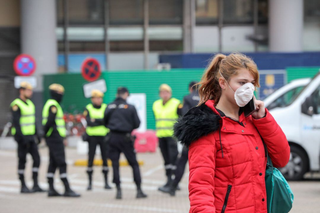 Una mujer con mascarilla circula cerca de donde se concentran efectivos de la Policía Nacional y del UME en las inmediaciones de la estación de tren Puerta de Atocha.