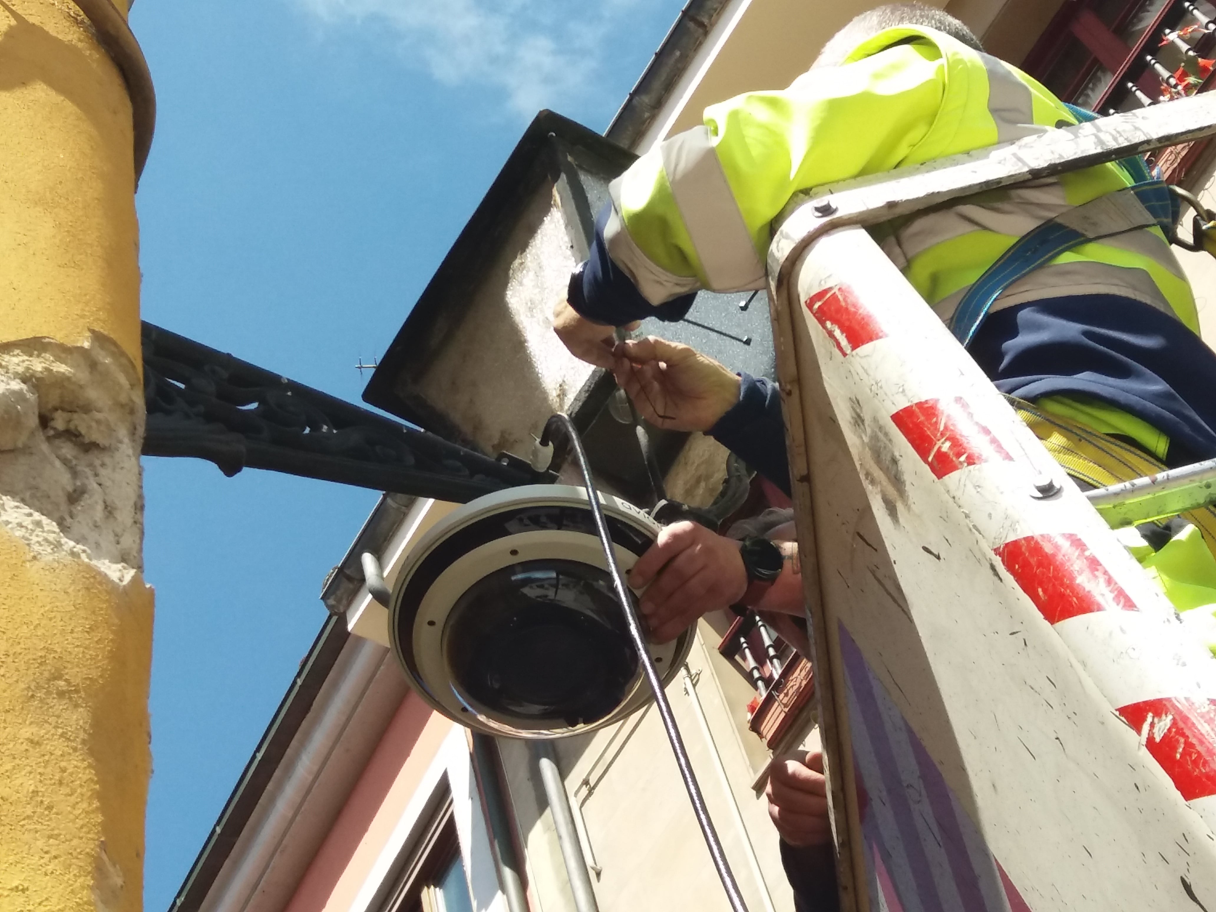 Los operarios de la empresa adjudicataria colocan la cámara en el brazo de una de las farolas existentes, para evitar afectar a fachadas u otros elementos