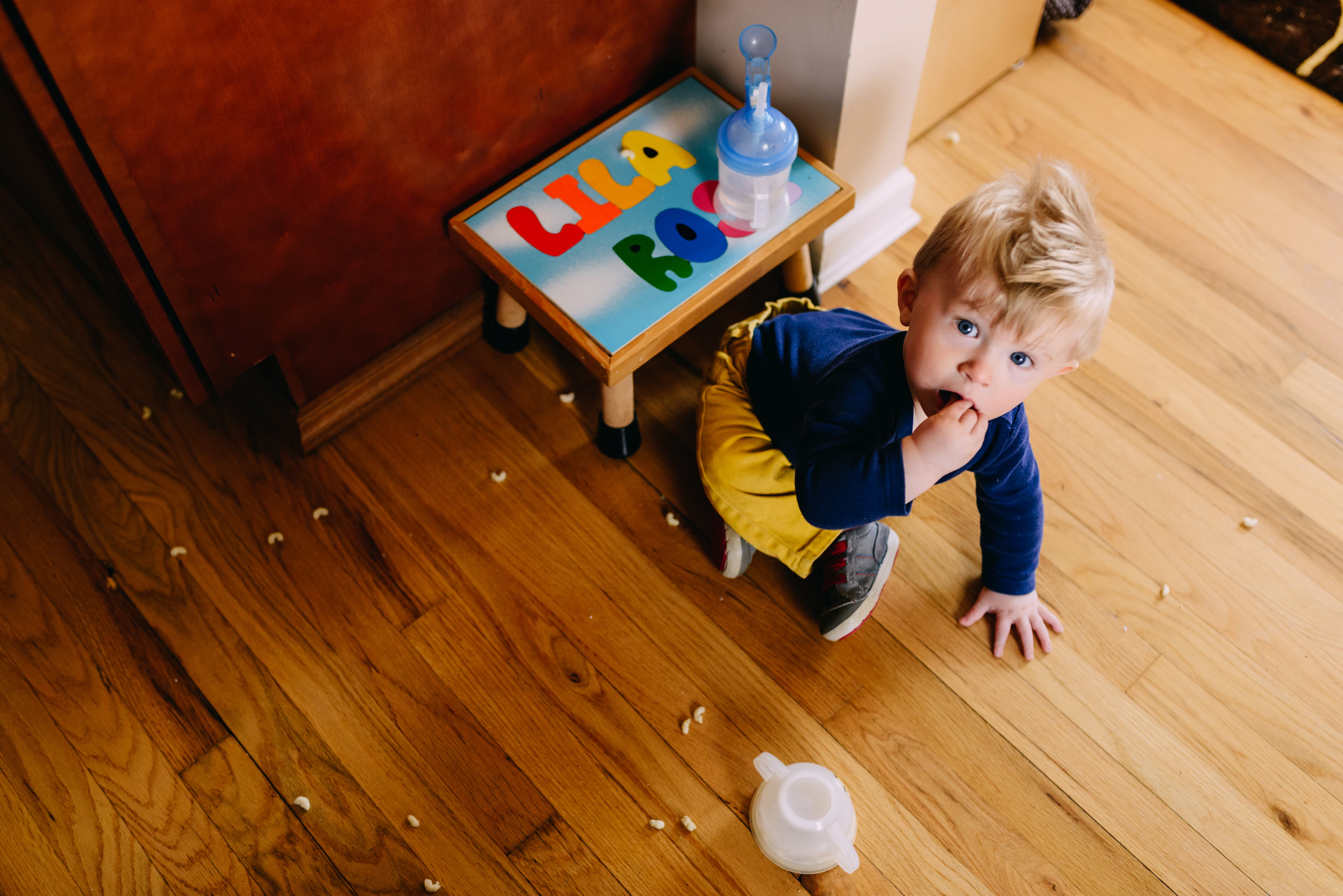 Un niño se come cereales que se le han caído por el suelo