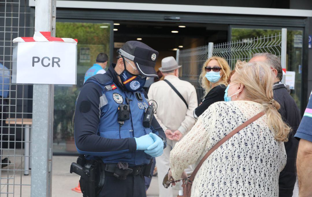 Un policía municipal pide la documentación a una mujer antes de entrar al Centro Cultural Lope de Vega, en la Zona Básica de Salud (ZBS) de Puente de Vallecas.