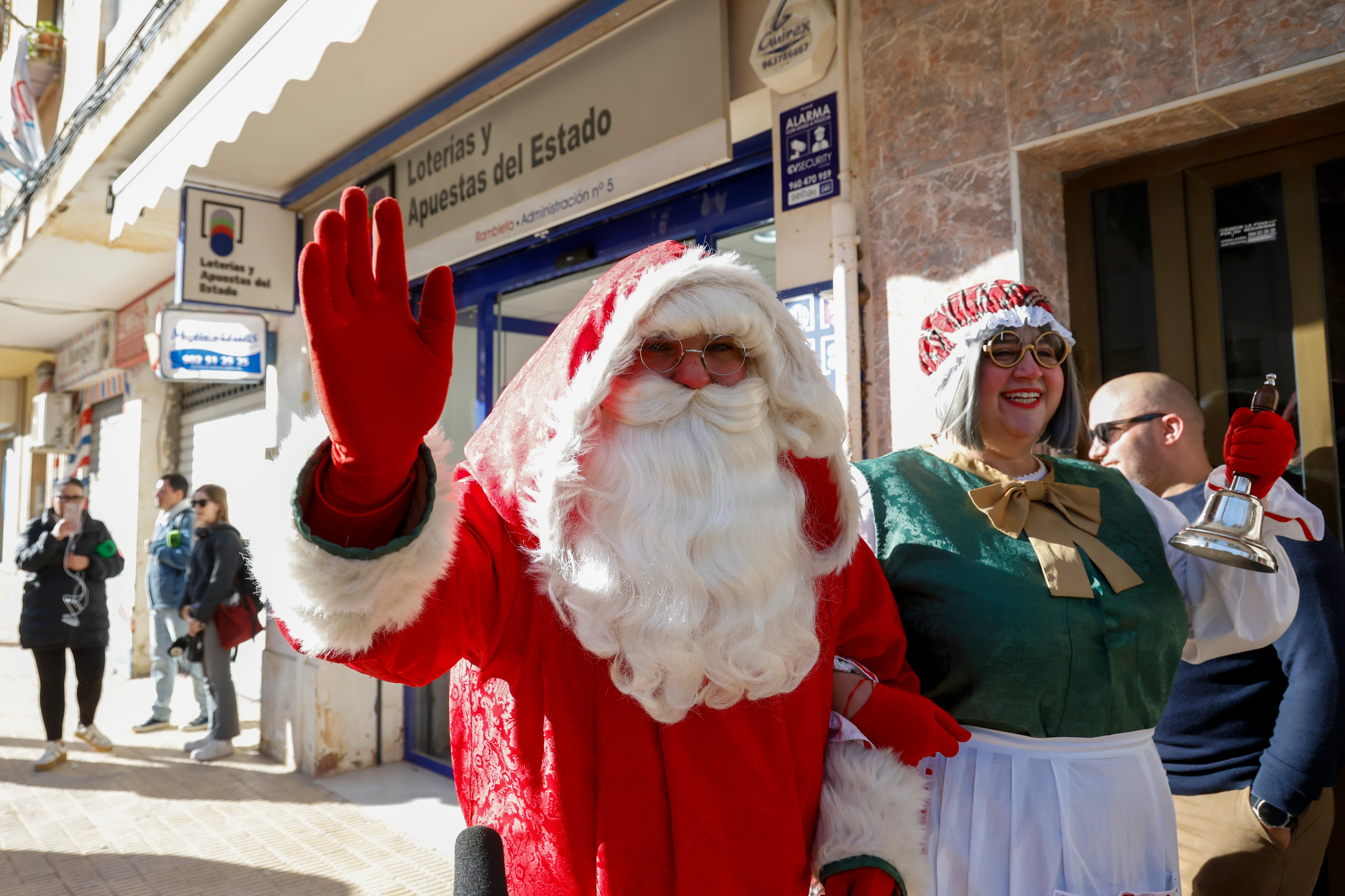 Una persona disfrazada de Papá Noel saluda ante la administración número 5 de Catarroja, en la zona cero de la dana del 29 de octubre, que ha vendido una serie del quinto premio, el 11.840.