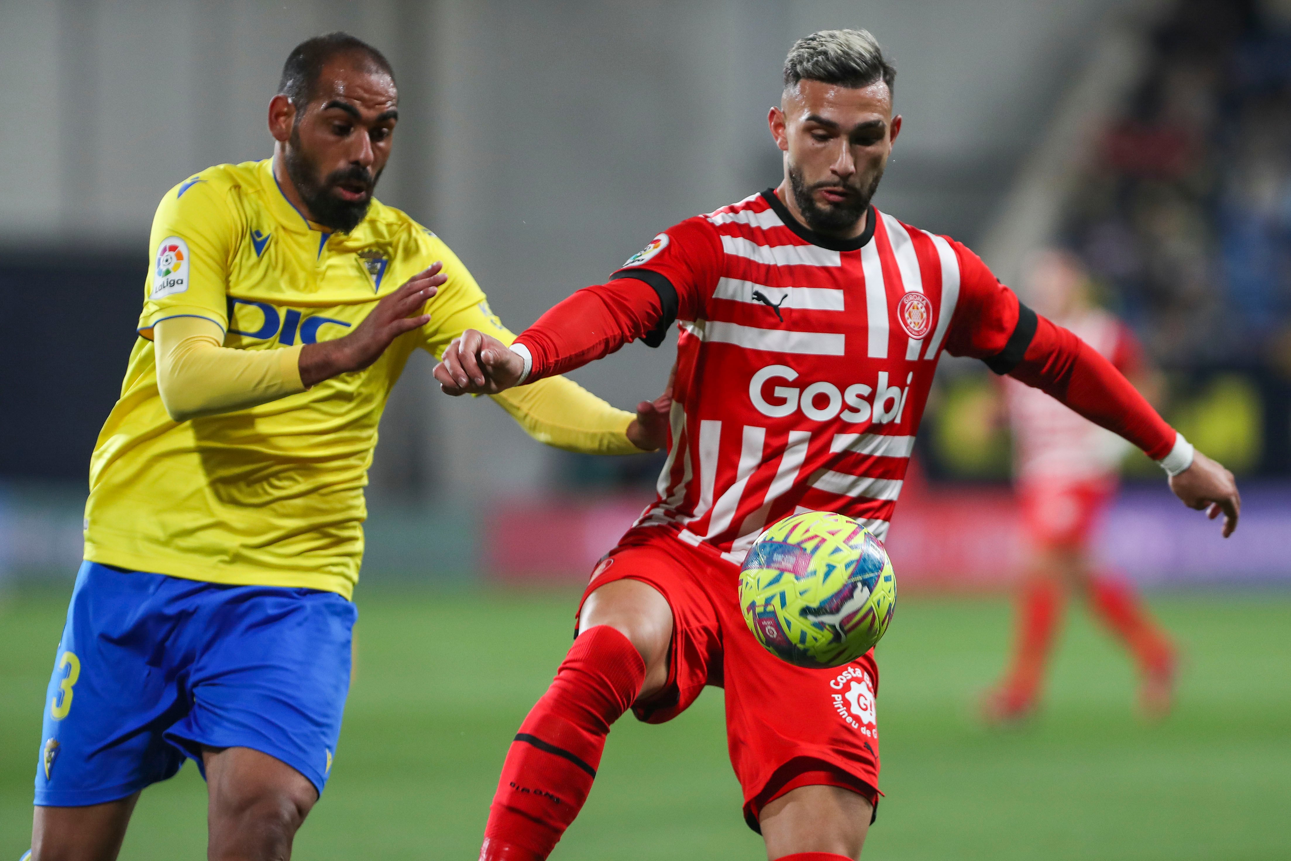 CÁDIZ, 10/02/2023.- El delantero del Girona Valentín Castellano (d) protege un balón ante Rafael Jiménez &quot;Fali&quot;, del Cádiz, durante el partido de Liga en Primera División entre Cádiz CF y Girona FC disputado este viernes en el estadio Nuevo Mirandilla. EFE/Román Ríos
