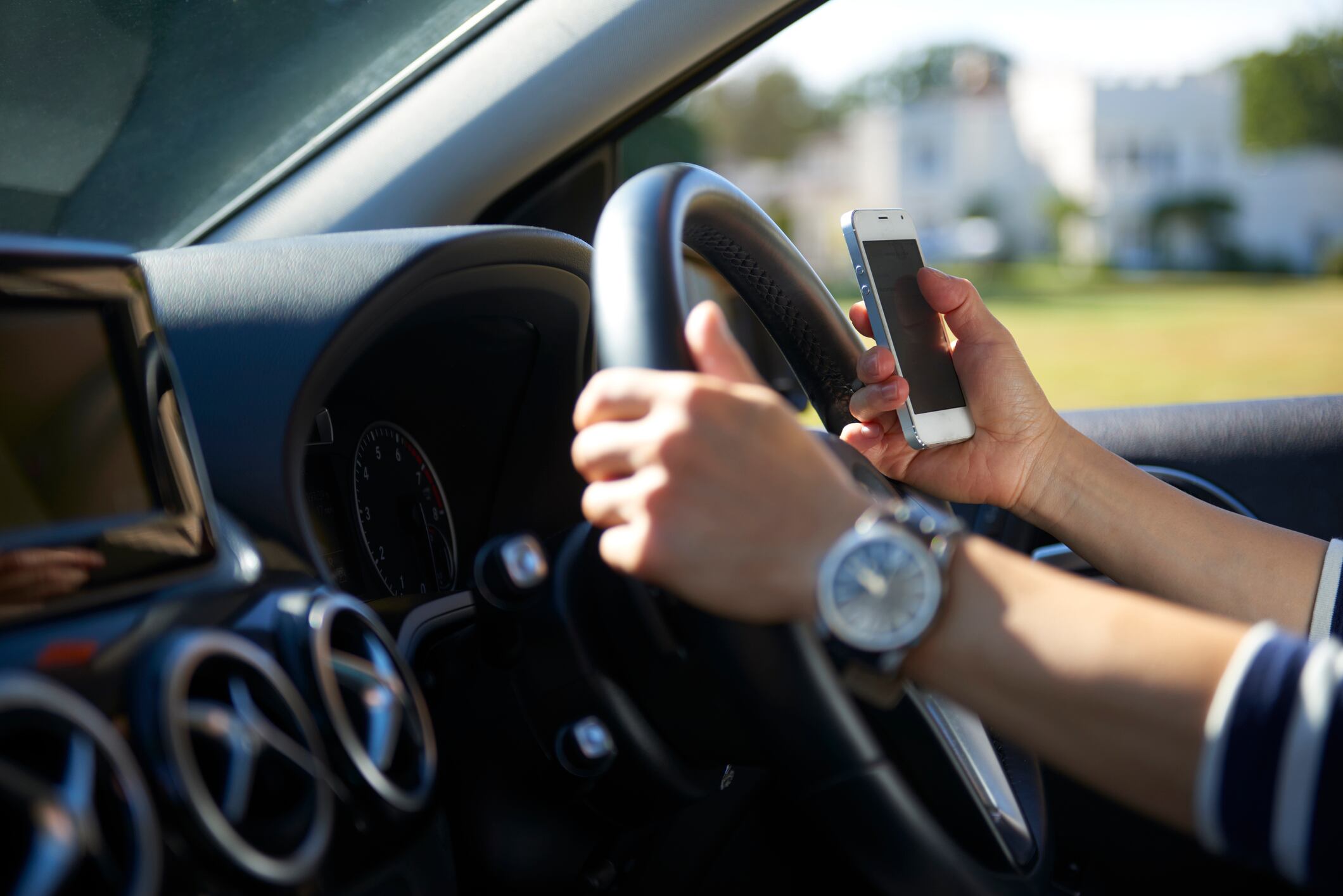 Una conductora al volante, mientras hace uso también de un smartphone