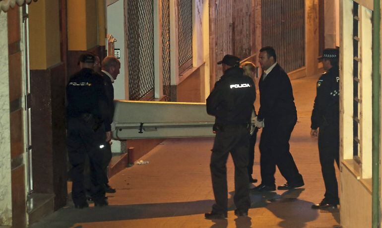 Miembros de los servicios funerarios, transportan el féretro con uno de los cadáveres.