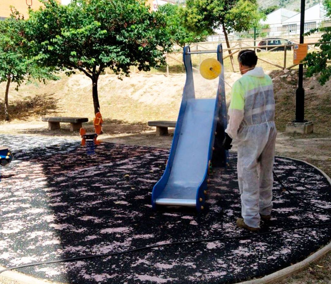 Un operario limpiando un tobogan de una zona de juegos infantiles de Alcoy.